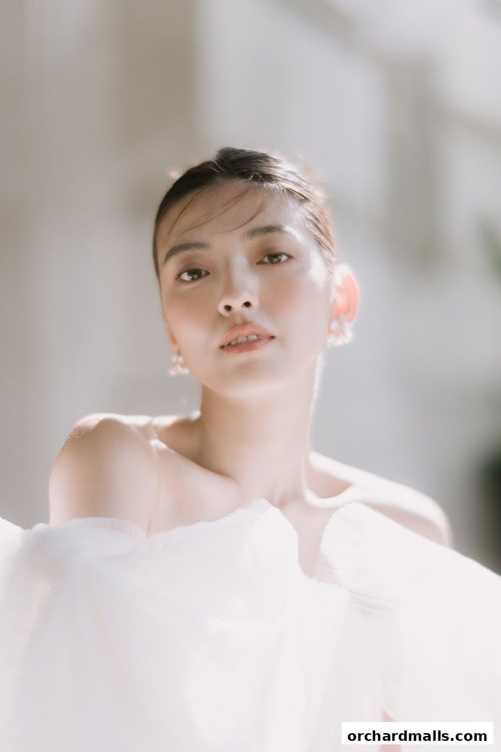 A close-up portrait of a woman with soft lighting and a white, flowing garment.
