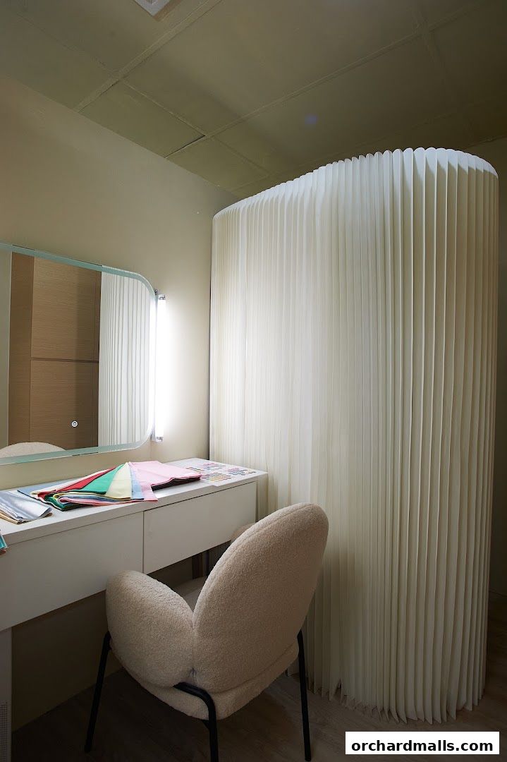 A makeup artist's vanity area with fabric swatches and a plush chair.