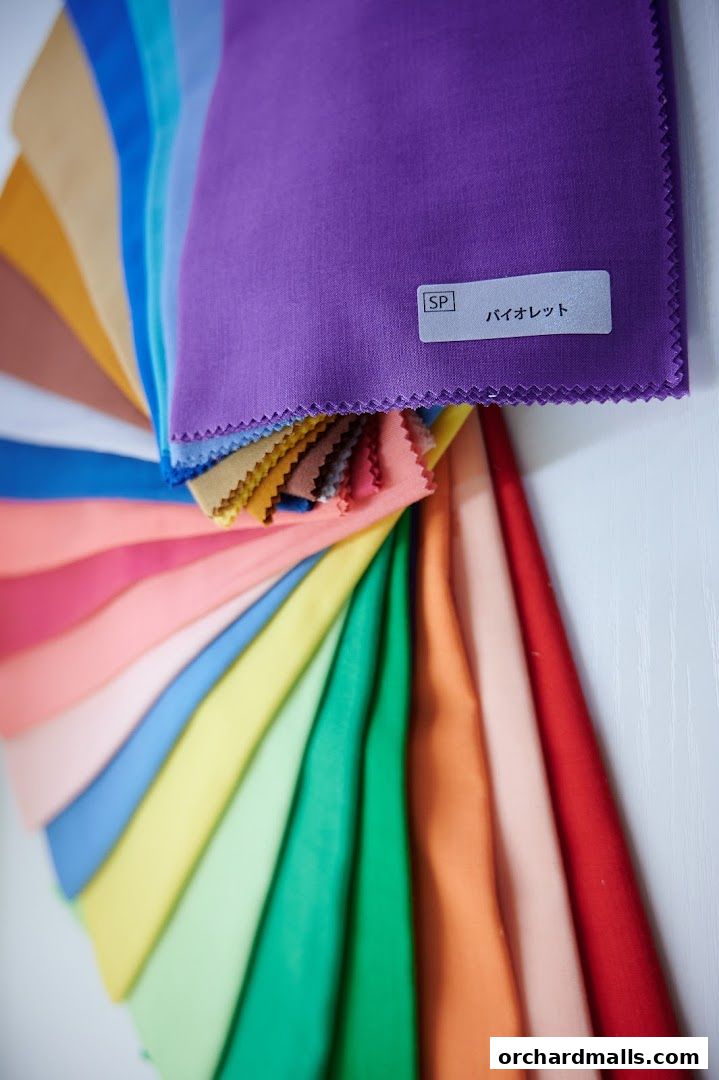 A fan of fabric swatches in various vibrant colors, with a label reading 'SP バイオレット'.