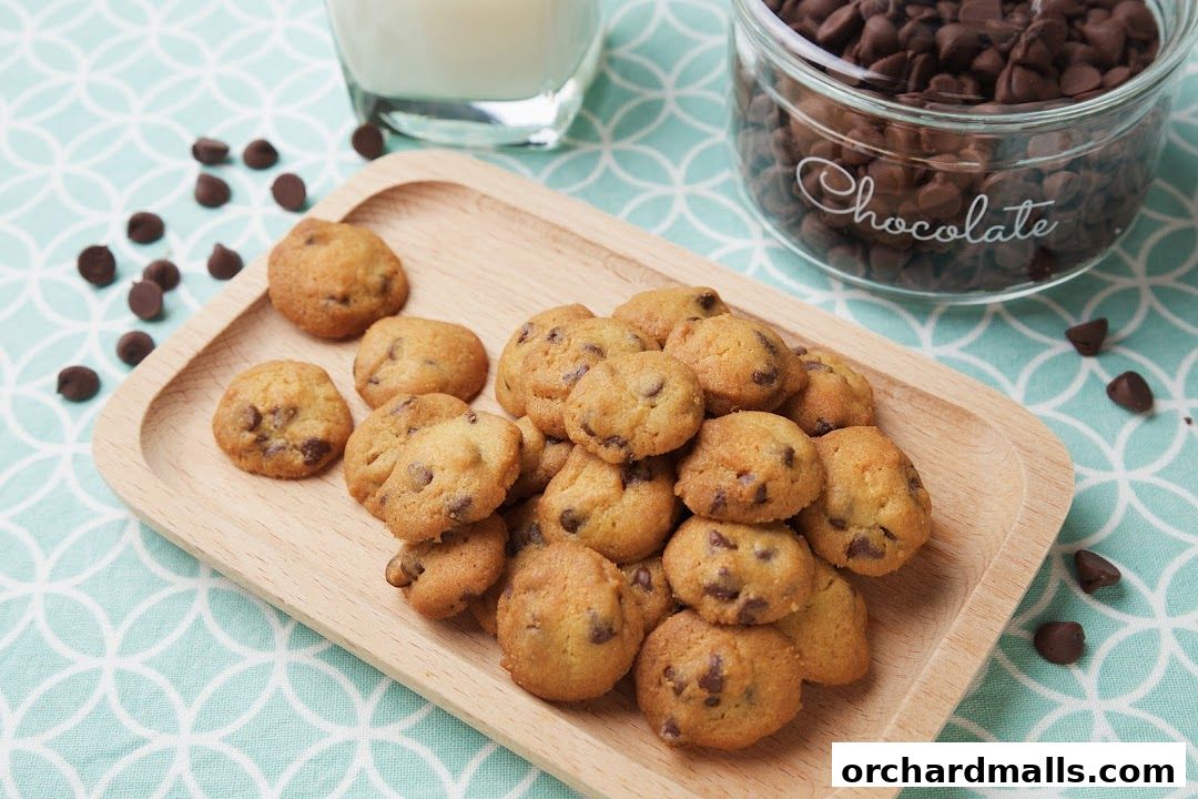 A wooden tray filled with freshly baked chocolate chip cookies and a glass of milk.