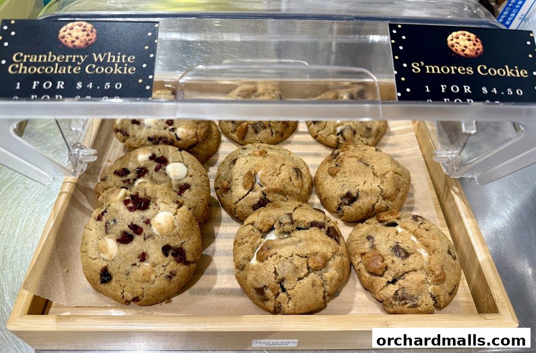 A display of freshly baked cookies, including Cranberry White Chocolate and S'mores flavors.