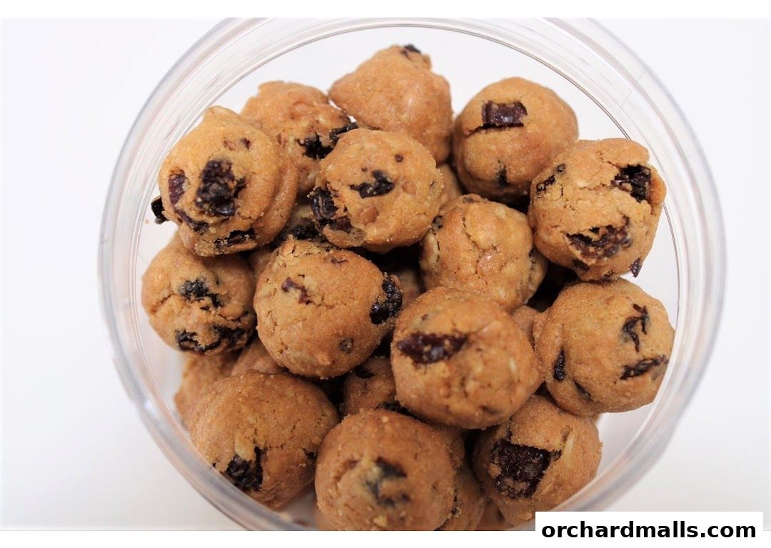 A clear plastic container filled with small, round cookies with visible dried fruit pieces.