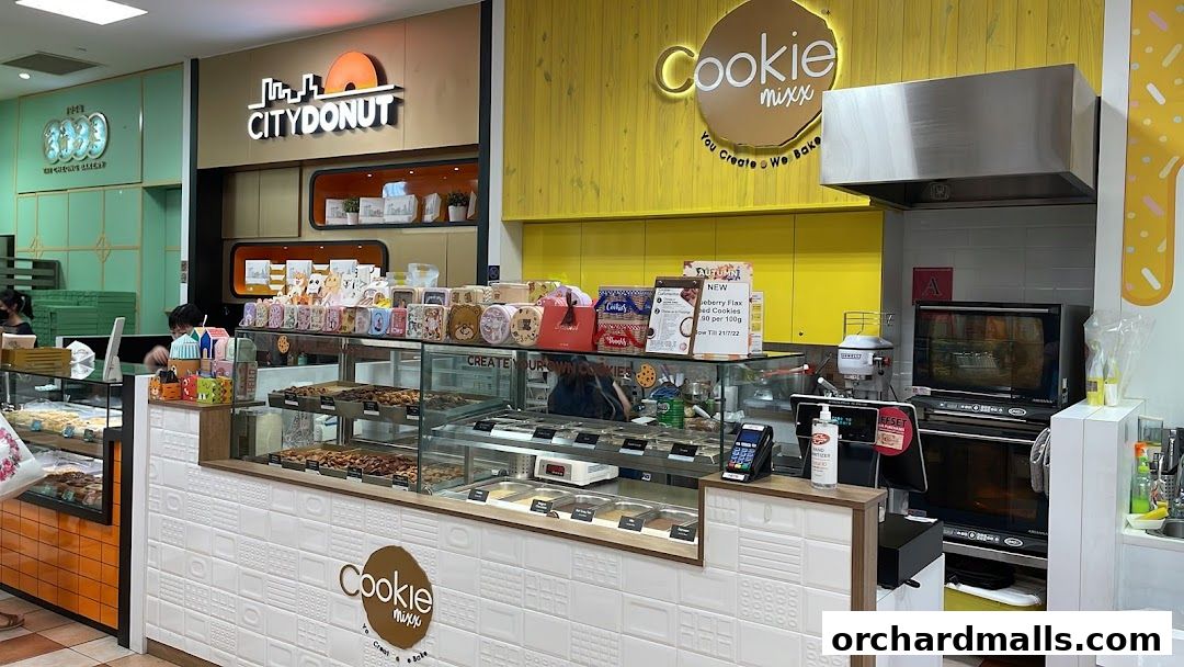 A brightly lit cookie shop counter with various cookies displayed in glass cases.