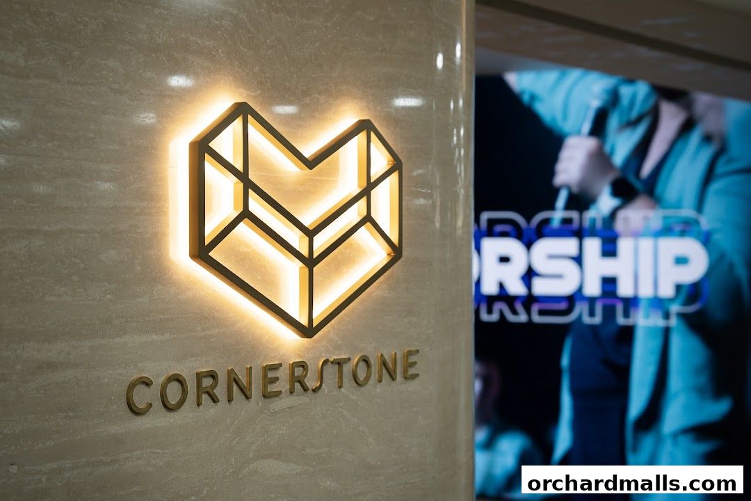 Cornerstone logo illuminated on a marble wall with a blurred background of a worship event.