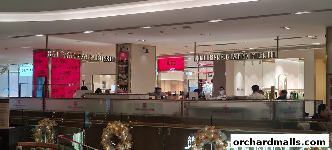 A view of several shops in a mall, including Hugo and Devialet, with people browsing.