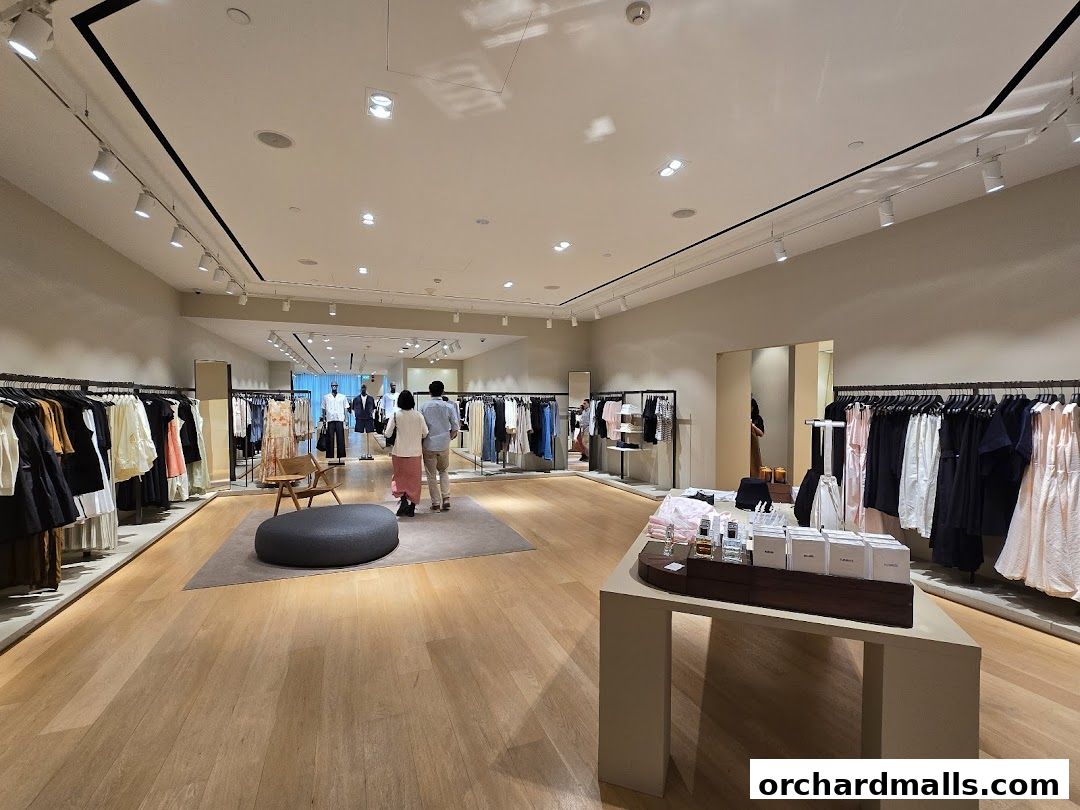Interior view of a modern clothing store with racks of apparel and display tables.