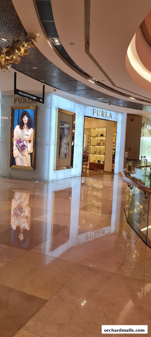 The exterior of a Furla store in a shopping mall, featuring a display window and the store's logo.