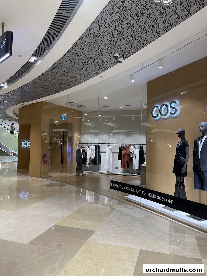 The entrance of a COS clothing store with mannequins and clothing racks visible inside.