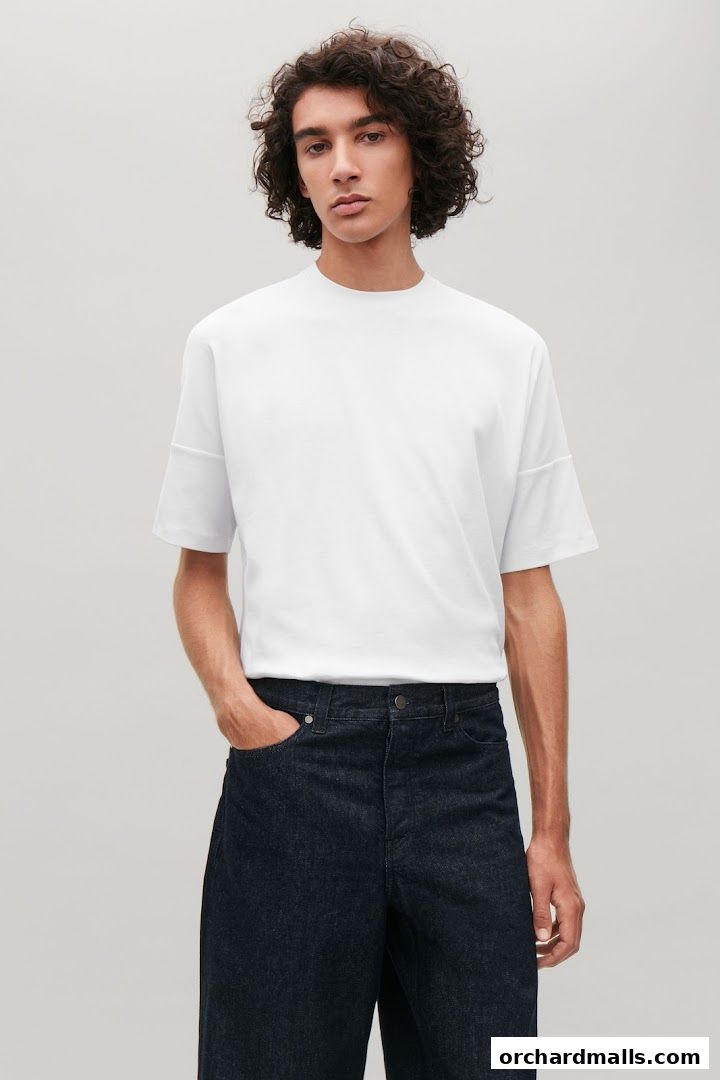 A man models a white t-shirt and dark denim jeans from COS.