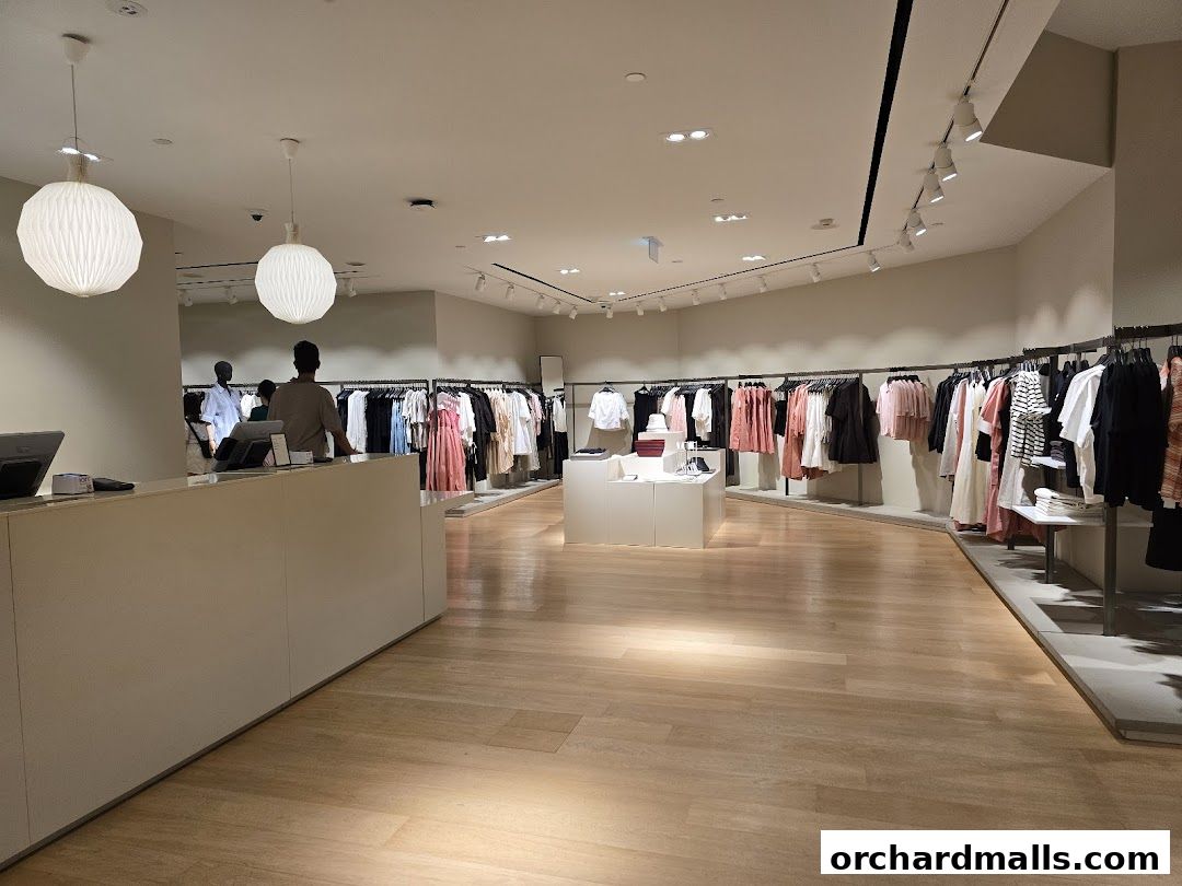 Interior view of a COS clothing store with racks of apparel and a checkout counter.