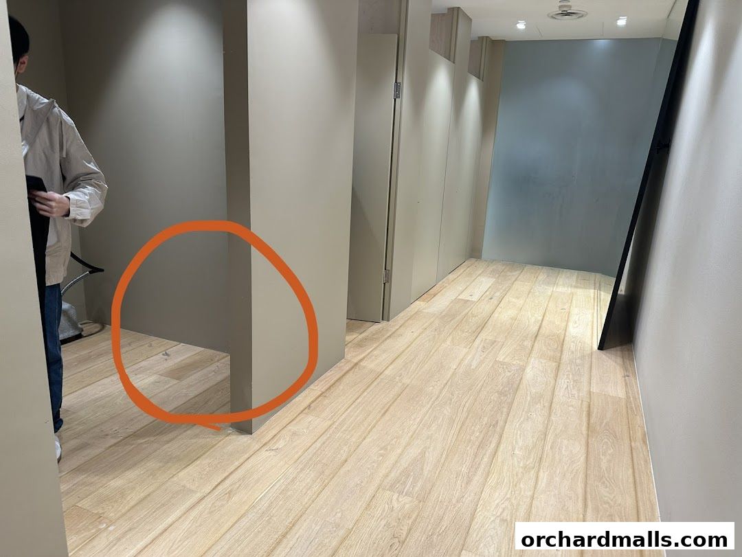 A person stands in a minimalist retail space with wooden floors and neutral walls.