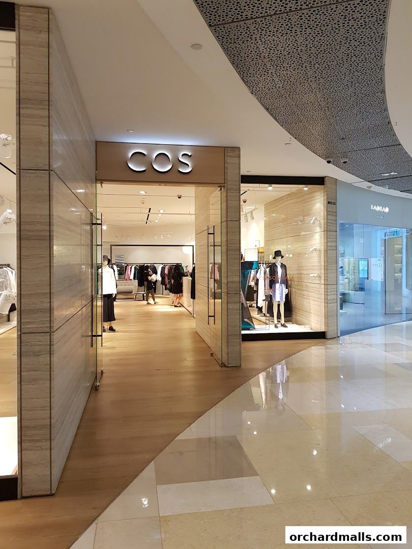 The entrance to the COS clothing store, showcasing mannequins and apparel inside.