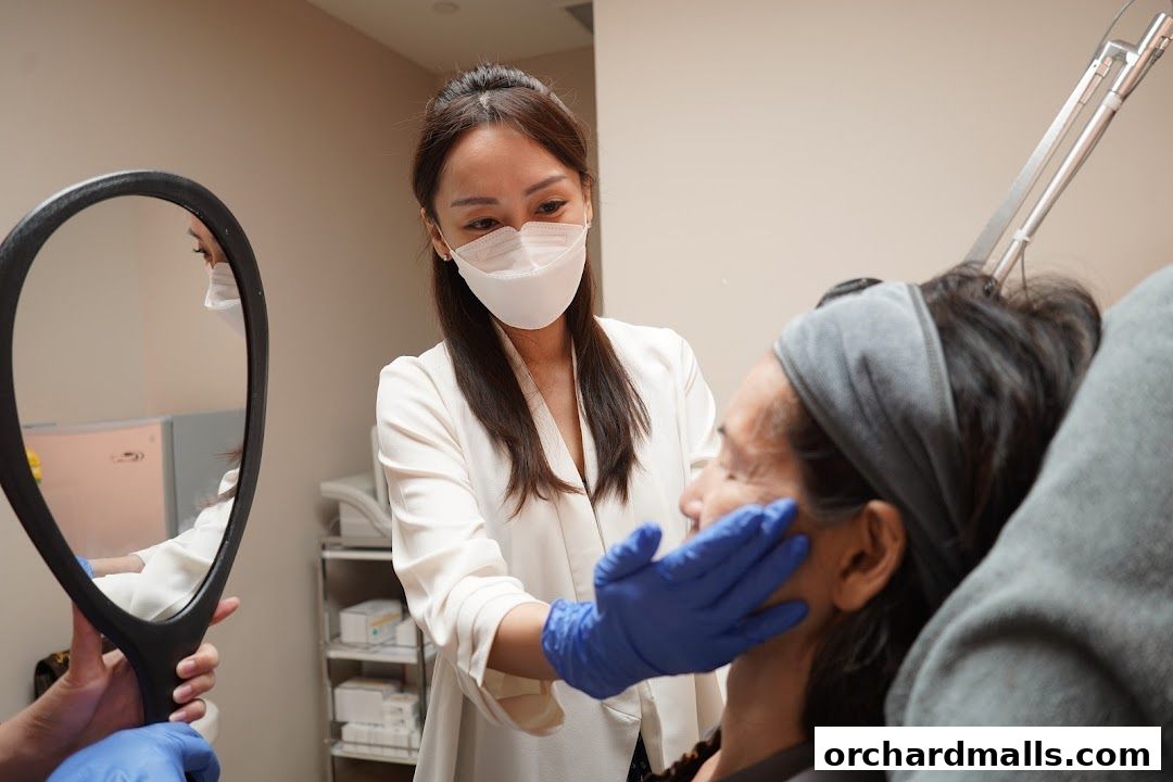 Aesthetician examining a client's face with a mirror in a clinic setting.