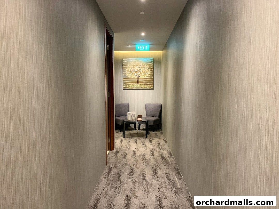 A hallway with textured walls, carpet, and a seating area with artwork.