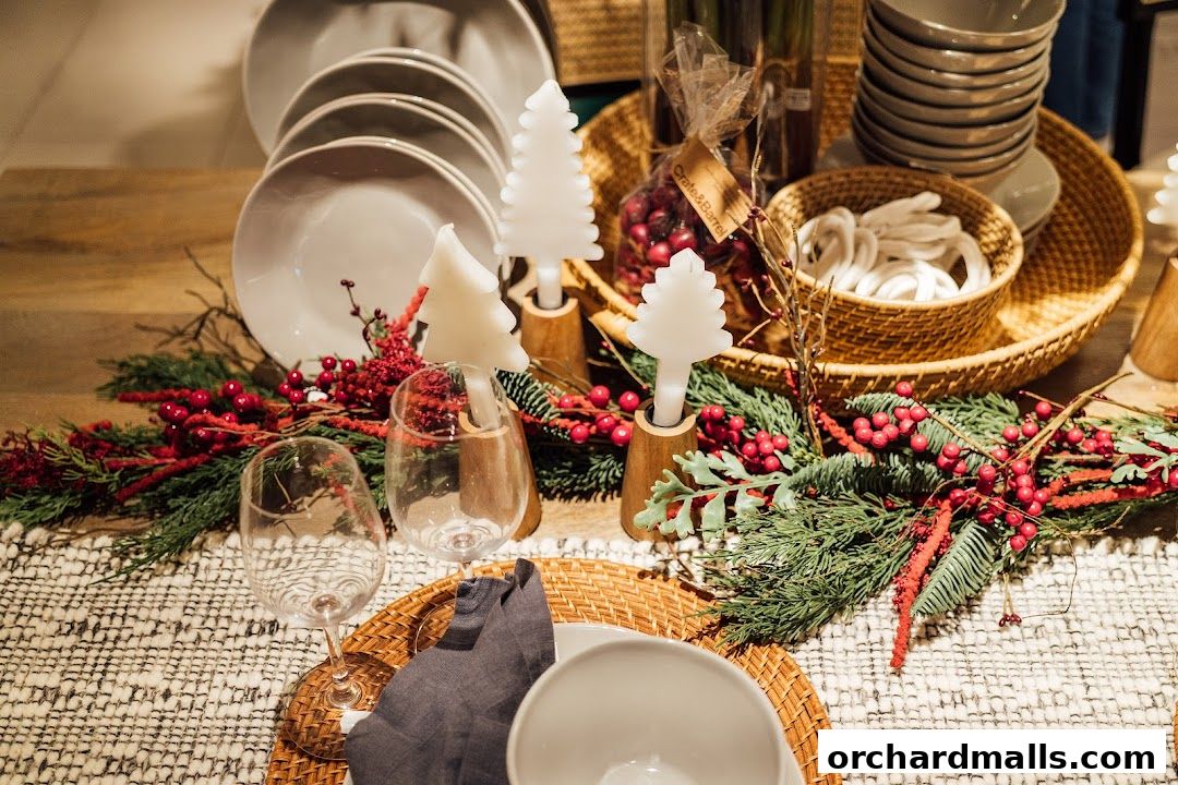 A festive table setting with Christmas tree candles, greenery, berries, and tableware.