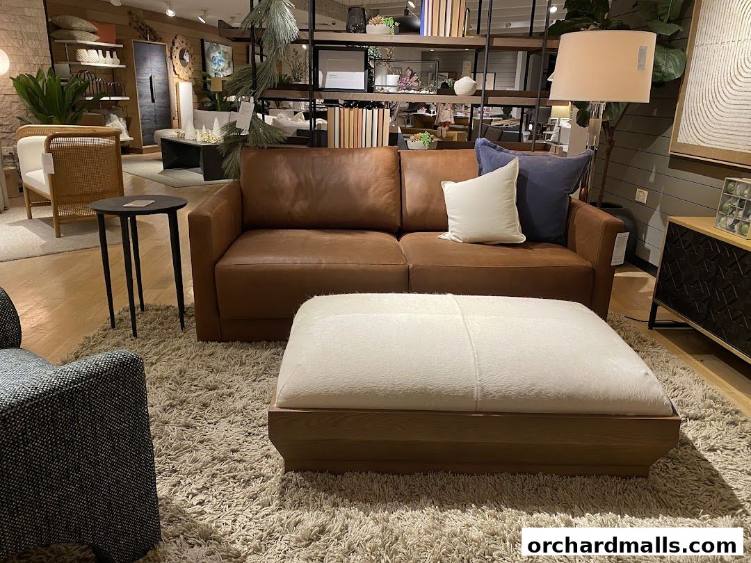 A stylish living room setup featuring a brown leather sofa, ottoman, and accent chair.