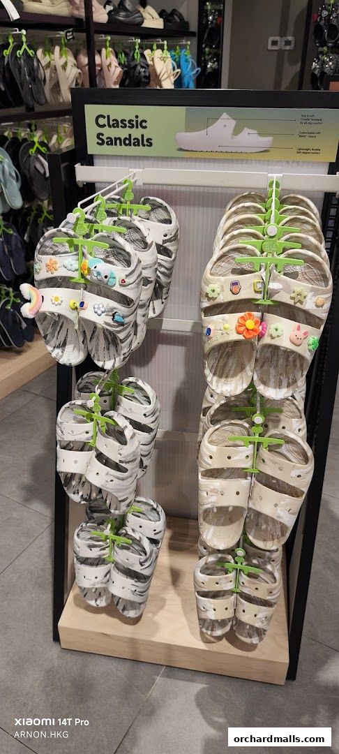 A display of Crocs classic sandals with various Jibbitz charms in a retail store.