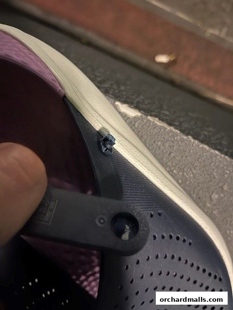 Close-up of a navy blue Crocs shoe with a purple interior and a hand adjusting the strap.