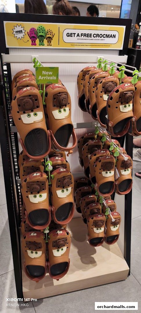 A display of brown Crocs shoes with cartoon car faces and a promotion for a free Crocman.