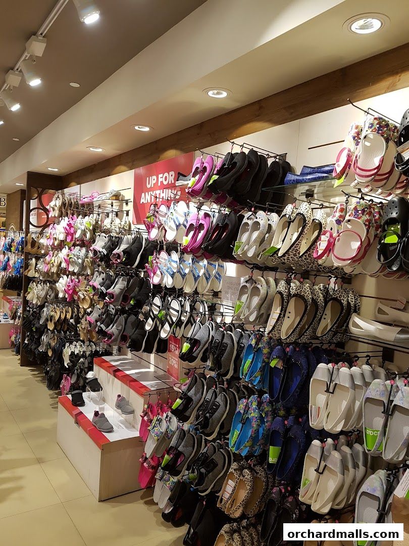 A wide selection of colorful Crocs shoes displayed on shelves and racks inside a store.