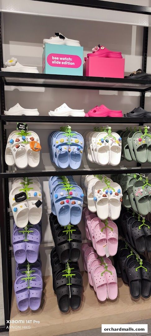 A display of colorful Crocs slides and clogs in various styles and colors.