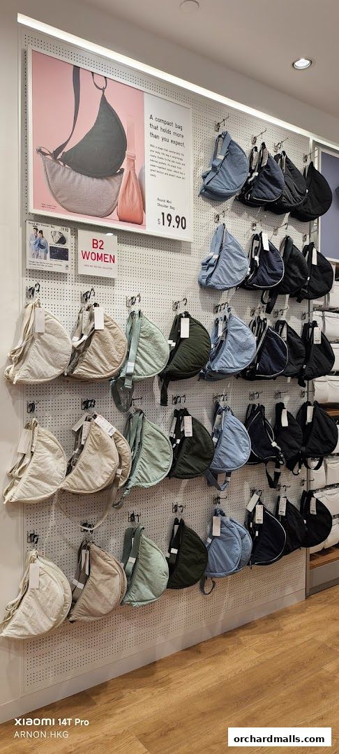 A display of various colored shoulder bags hanging on a pegboard wall in a retail store.