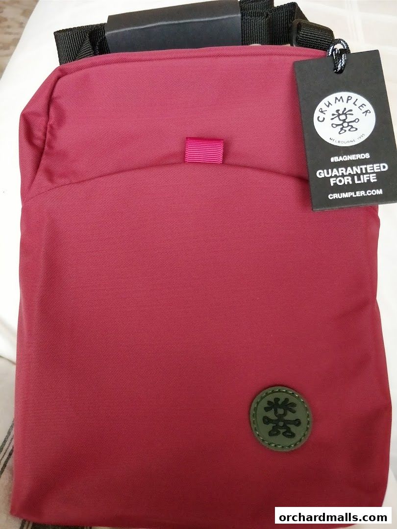 A close-up of a red Crumpler bag with a tag and logo.