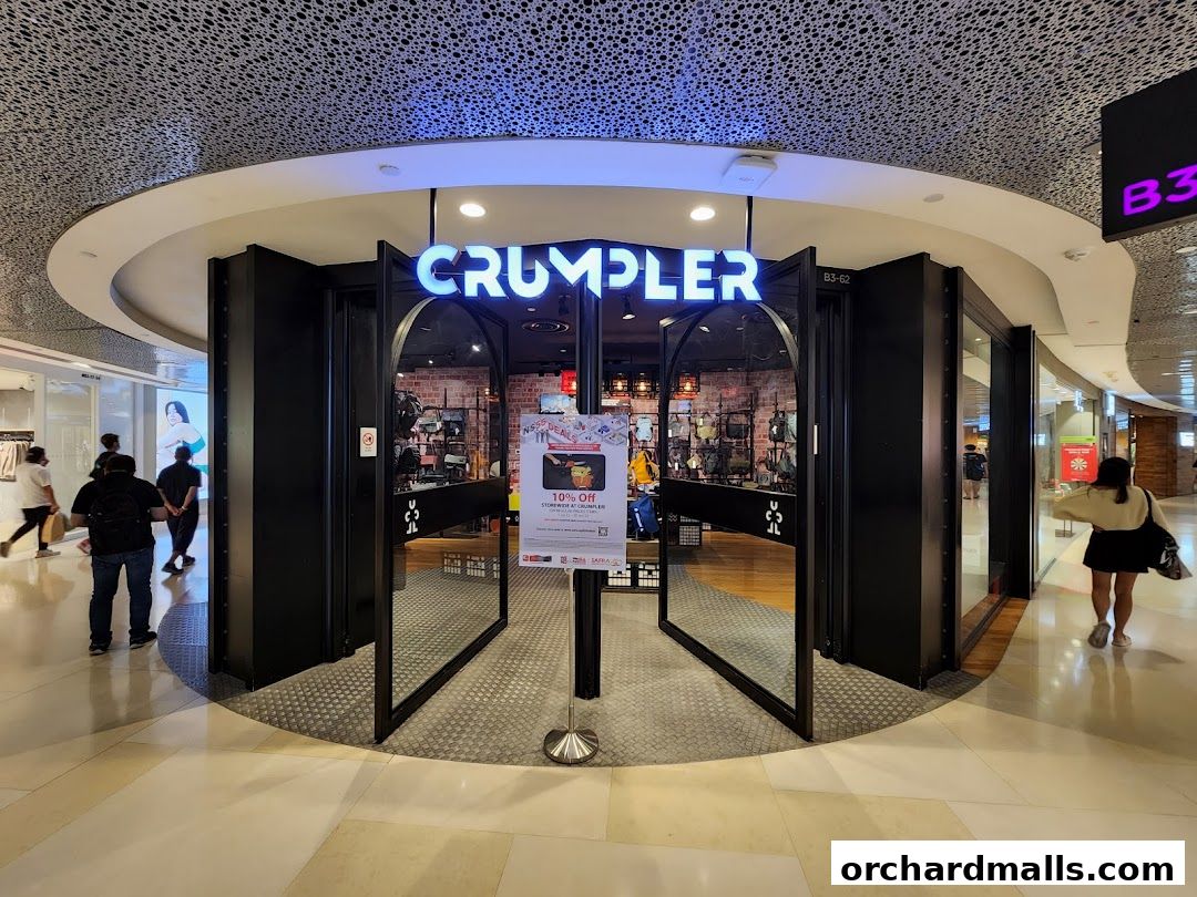 The entrance of a Crumpler store with bags displayed inside and a promotional sign.