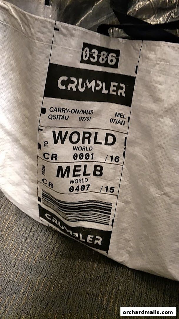 A close-up of a Crumpler bag with travel tag-inspired branding and a barcode.