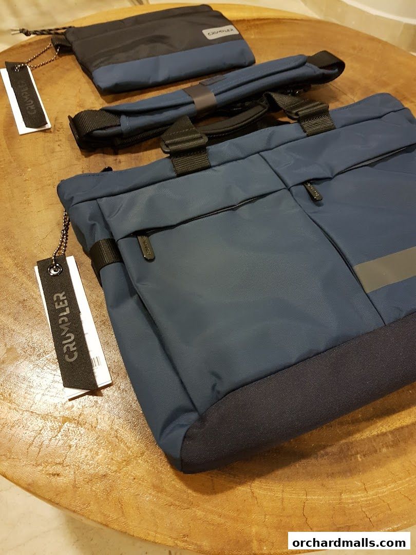 A close-up shot of navy blue Crumpler bags and accessories on a wooden surface.