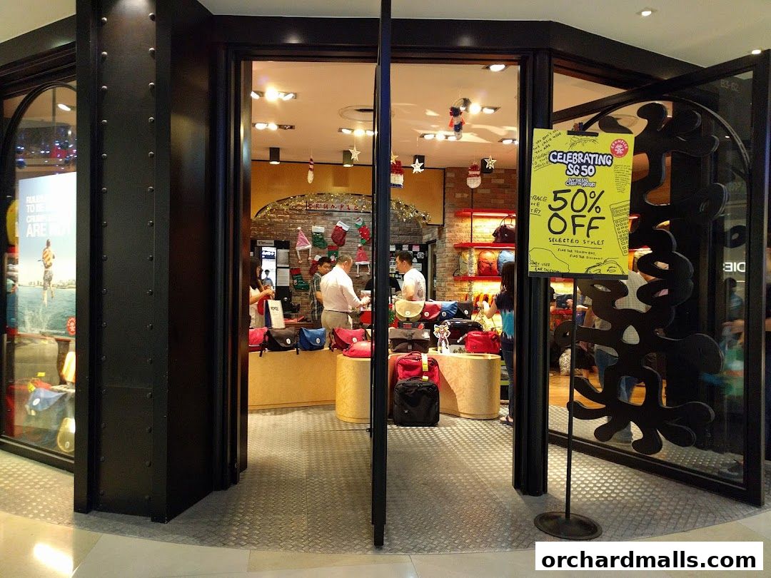 The entrance to a Crumpler shop with bags displayed and a 50% off sale sign.