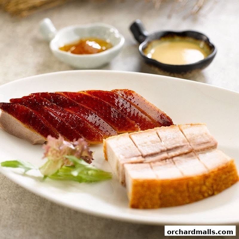 A plate of roasted duck and crispy pork belly with dipping sauces.