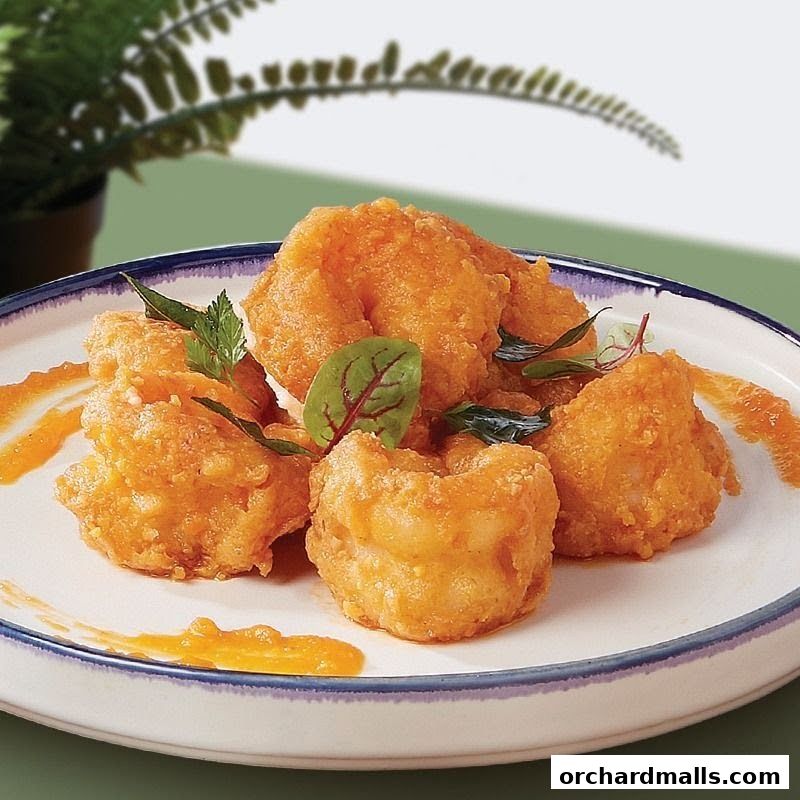 A plate of golden-brown fried shrimp with a drizzle of sauce and garnished with herbs.