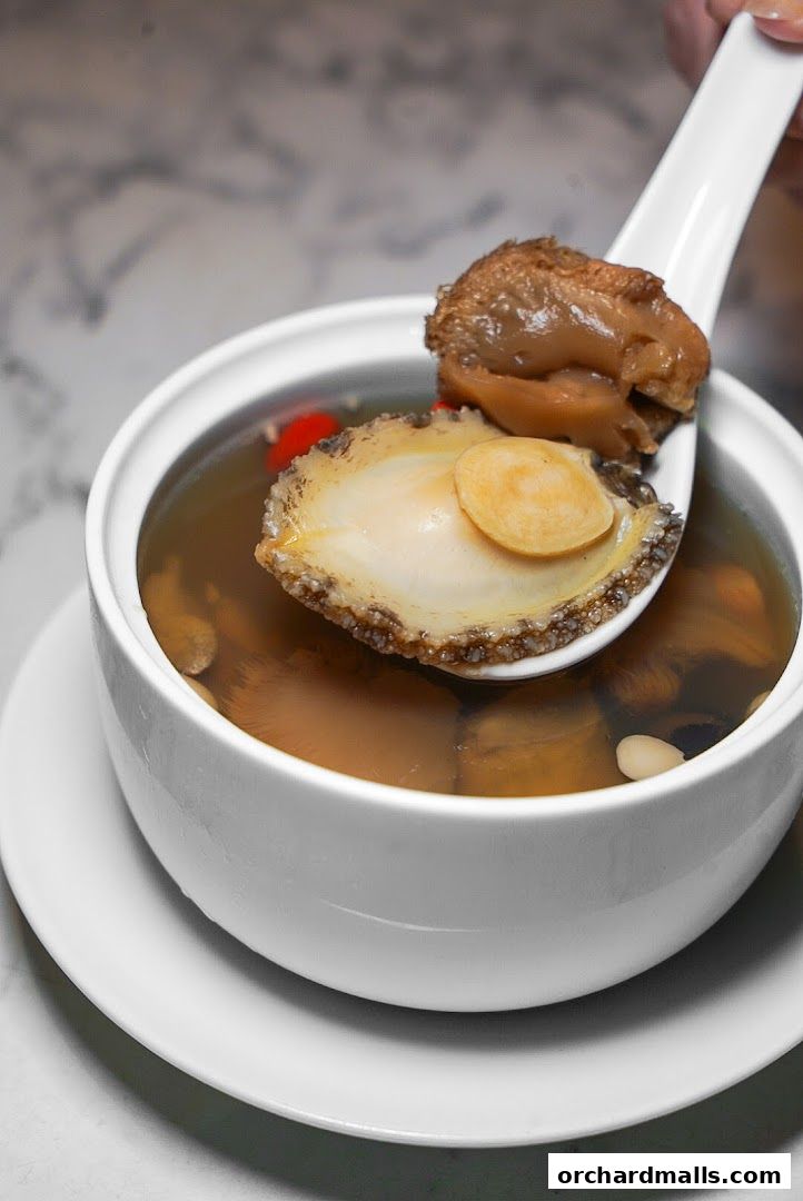 A close-up of a spoonful of abalone soup with other ingredients.