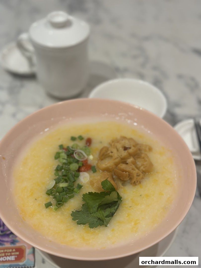 A bowl of congee with toppings and a tea cup on a marble table.