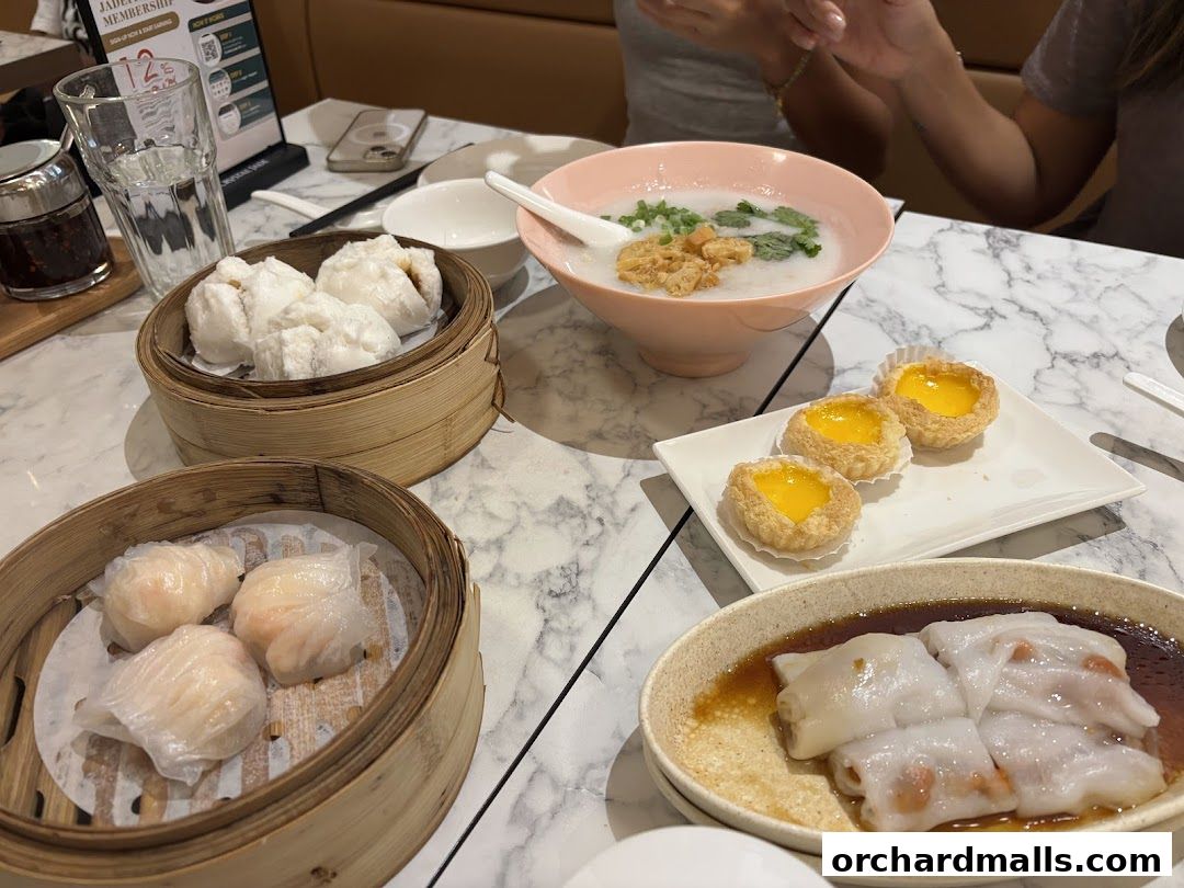 A table laden with various dim sum dishes, including dumplings, congee, and egg tarts.