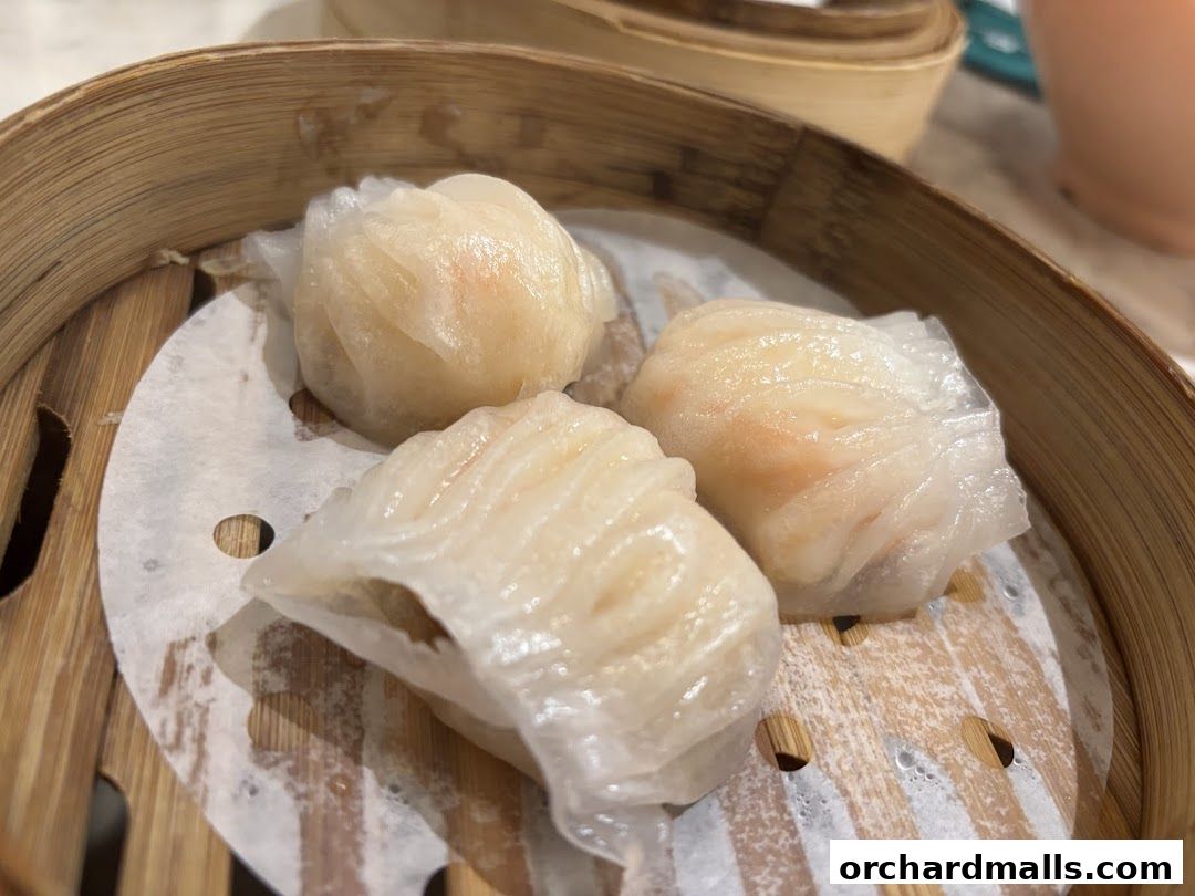 Three delicate steamed shrimp dumplings served in a bamboo steamer.