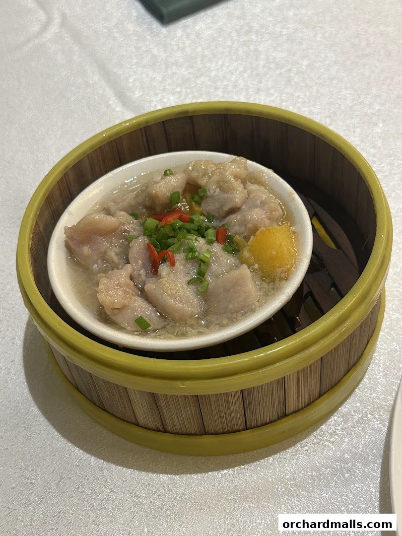 A close-up of a steamed dish with meat and vegetables in a bamboo steamer.