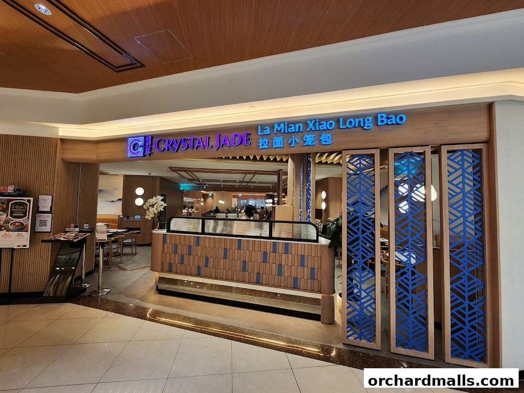The exterior of Crystal Jade restaurant, featuring its name and a sign for La Mian Xiao Long Bao.