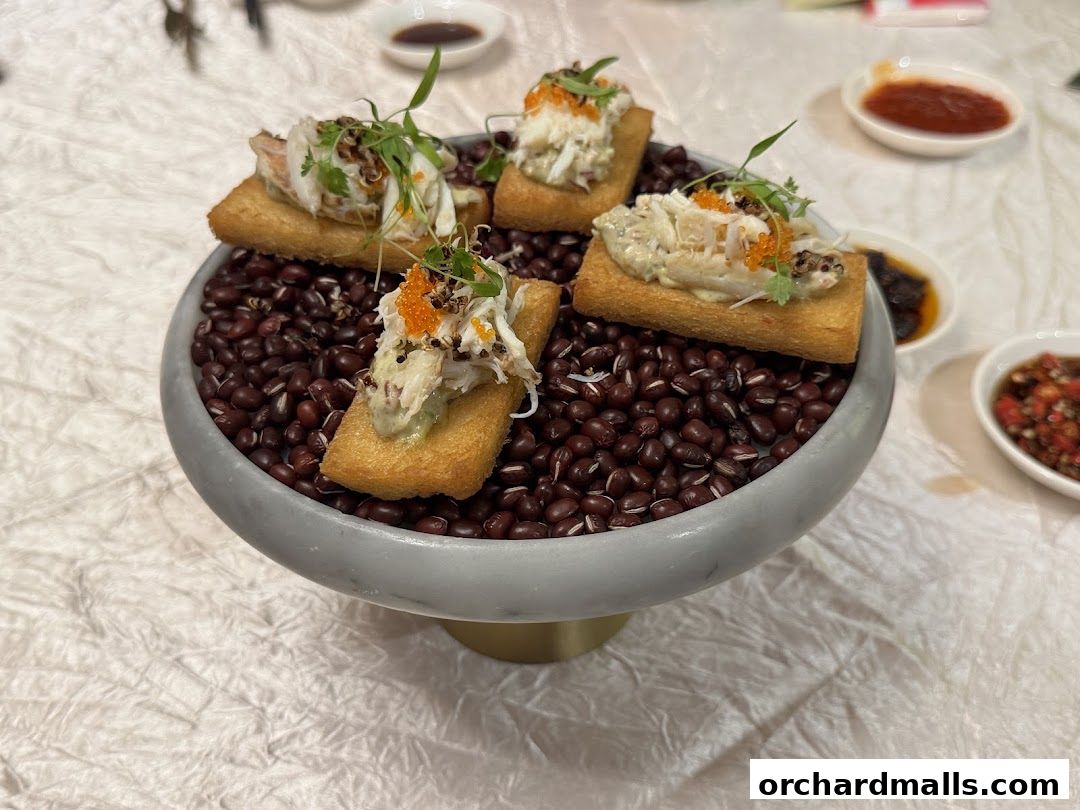 A decorative bowl filled with red beans, topped with four appetizers featuring crab meat.