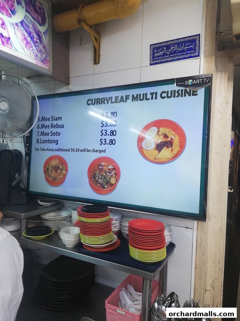 A digital menu board displays various noodle dishes and their prices at Curryleaf Multi Cuisine.