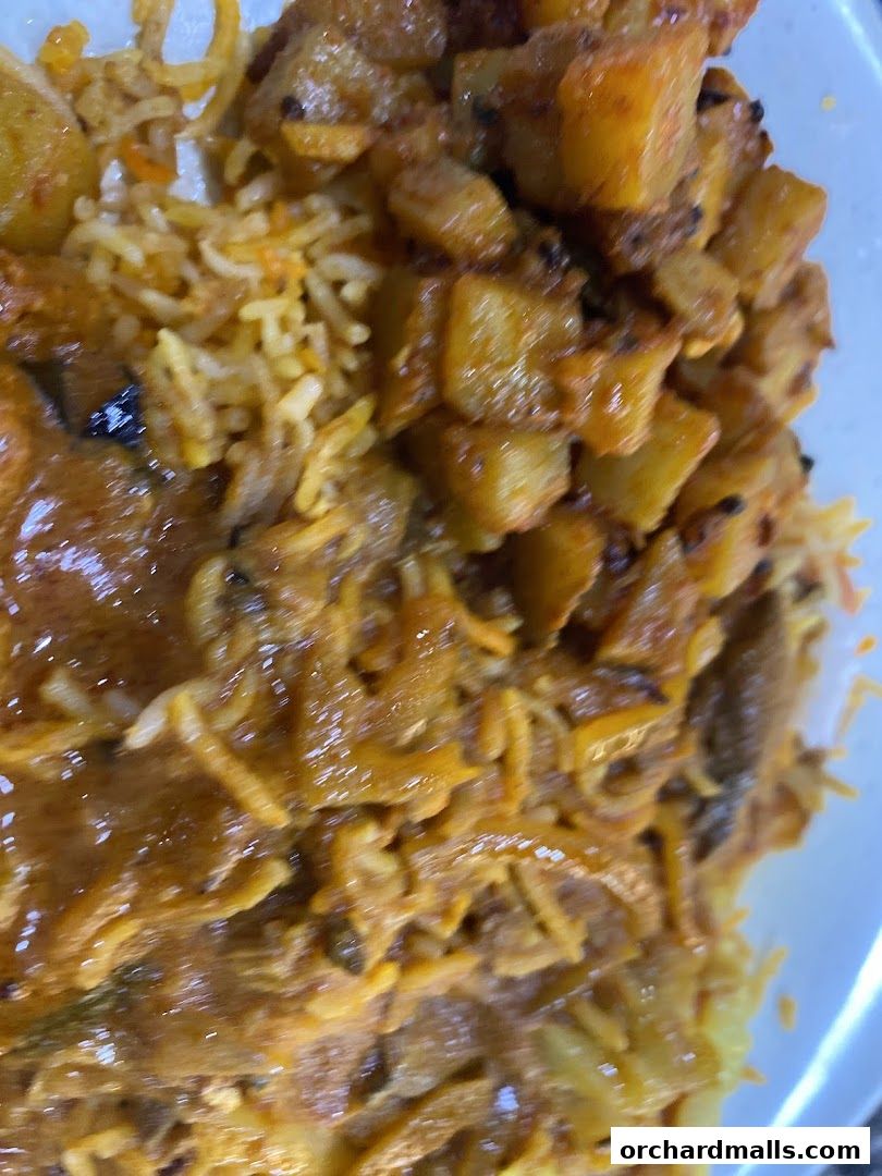 A close-up shot of a delicious Indian dish with rice and potatoes in a rich sauce.