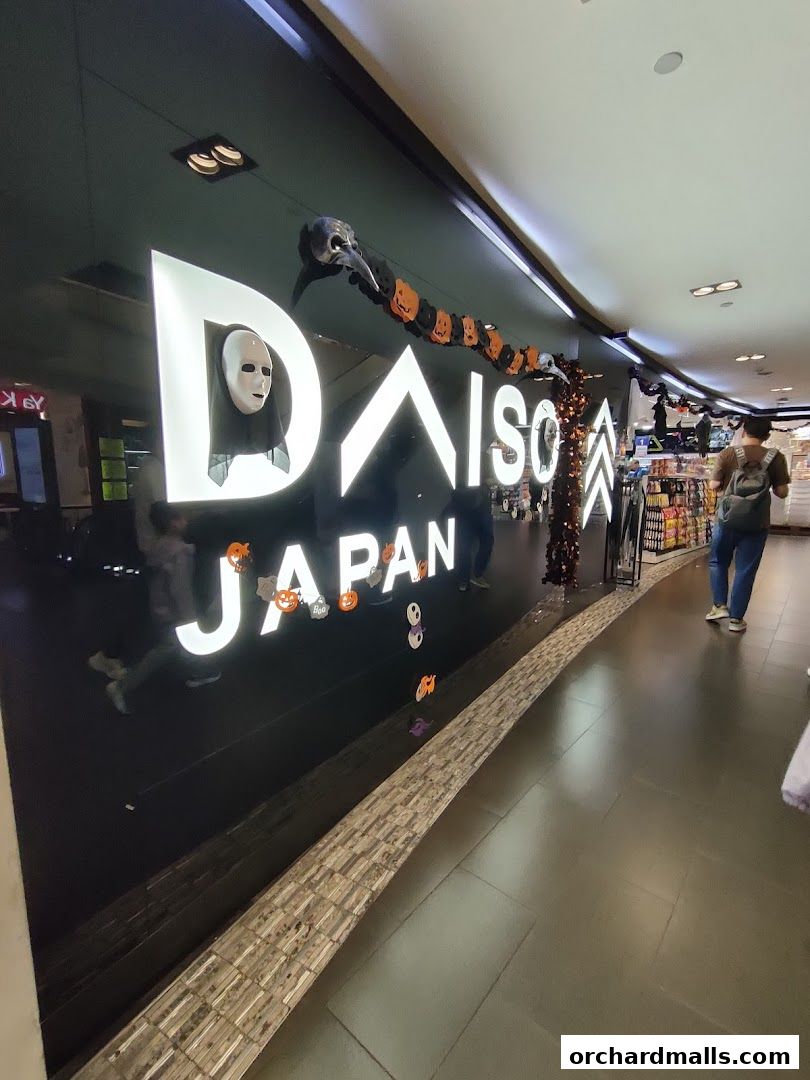 The DAISO JAPAN store entrance with Halloween decorations and a person walking by.