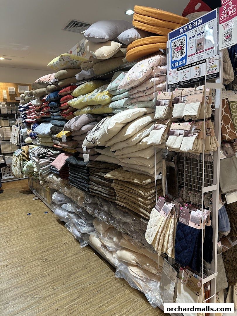 A wide selection of pillows, cushions, and textiles neatly stacked on shelves in a retail store.