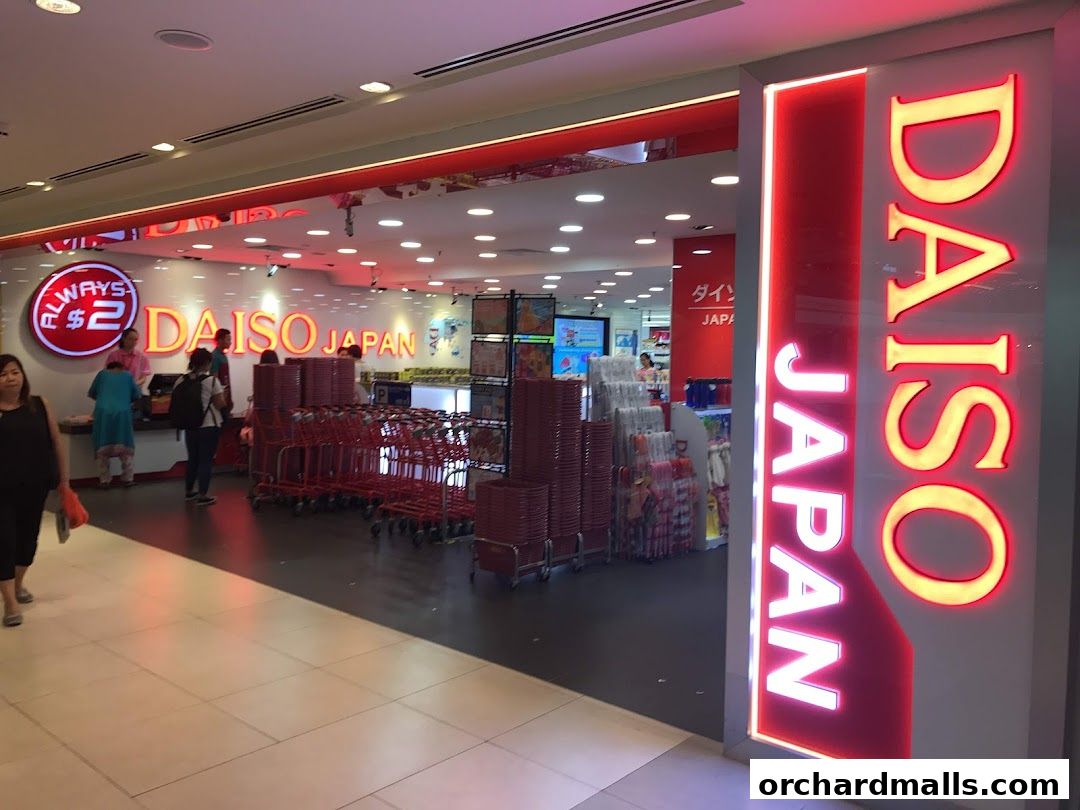 The entrance to a brightly lit Daiso Japan store with a prominent neon sign and shopping carts.