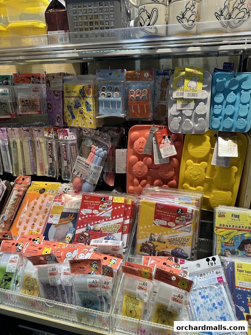 A display of various Disney-themed kitchenware and party supplies, including silicone molds and lunch boxes.