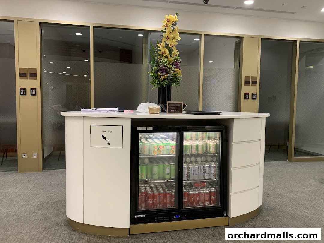 A counter with a mini-fridge stocked with drinks and a floral arrangement.