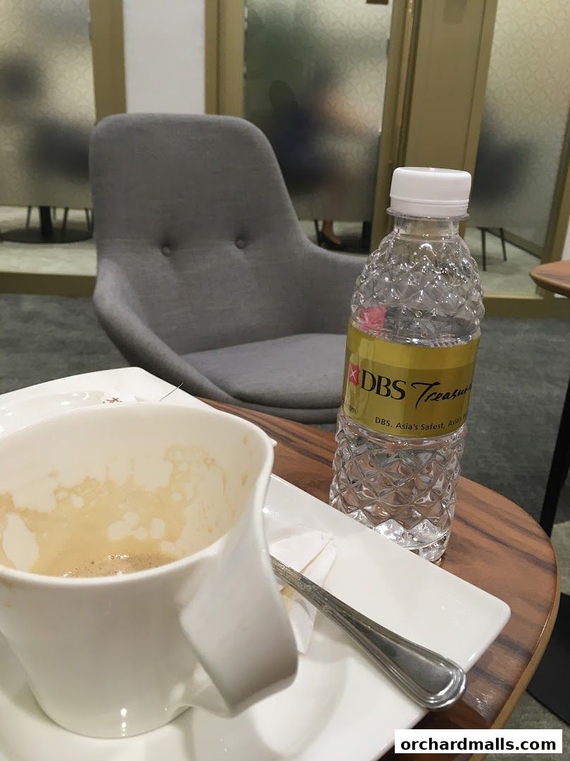 A coffee cup and a bottle of water on a table at DBS Treasures Ngee Ann City.