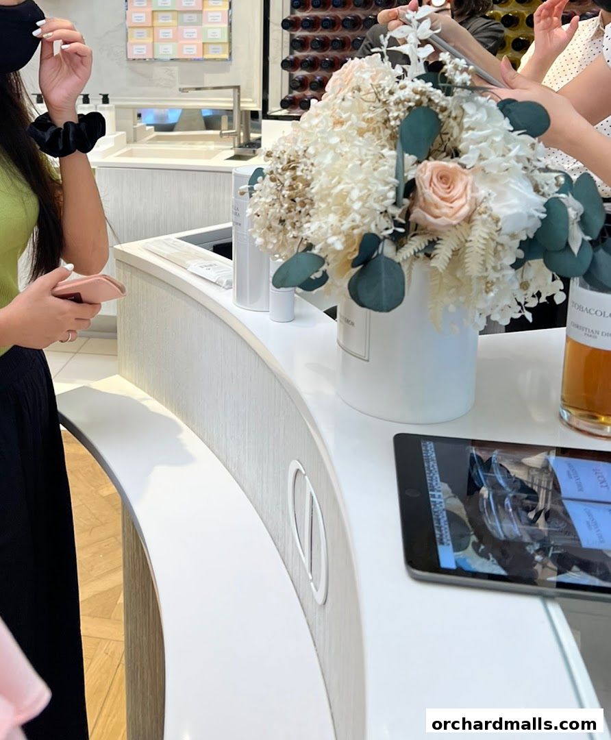 A customer at the Dior Beauty counter with a floral arrangement and tablet.