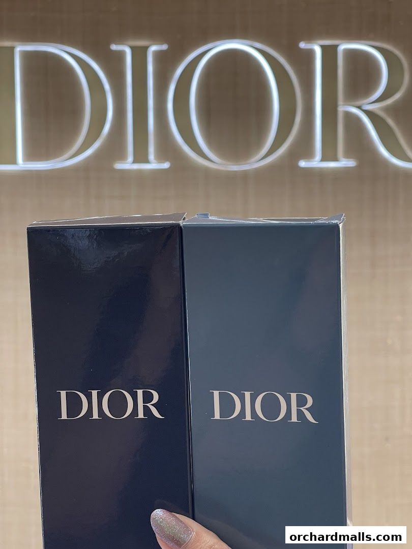 Two Dior beauty product boxes are displayed in front of a large illuminated Dior logo.